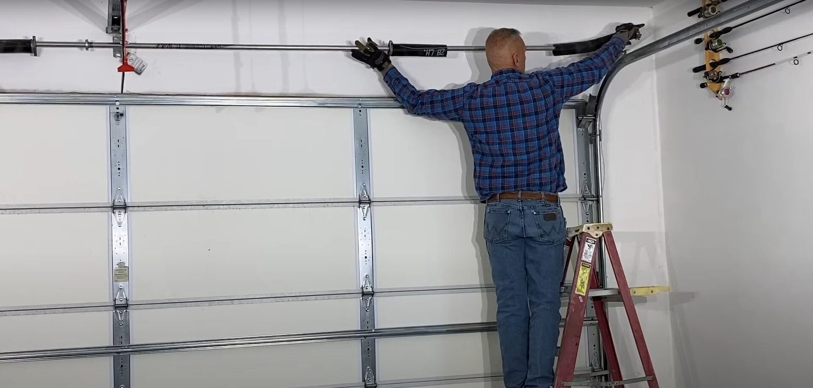 Technician inspecting garage door springs for security risks in a residential home.